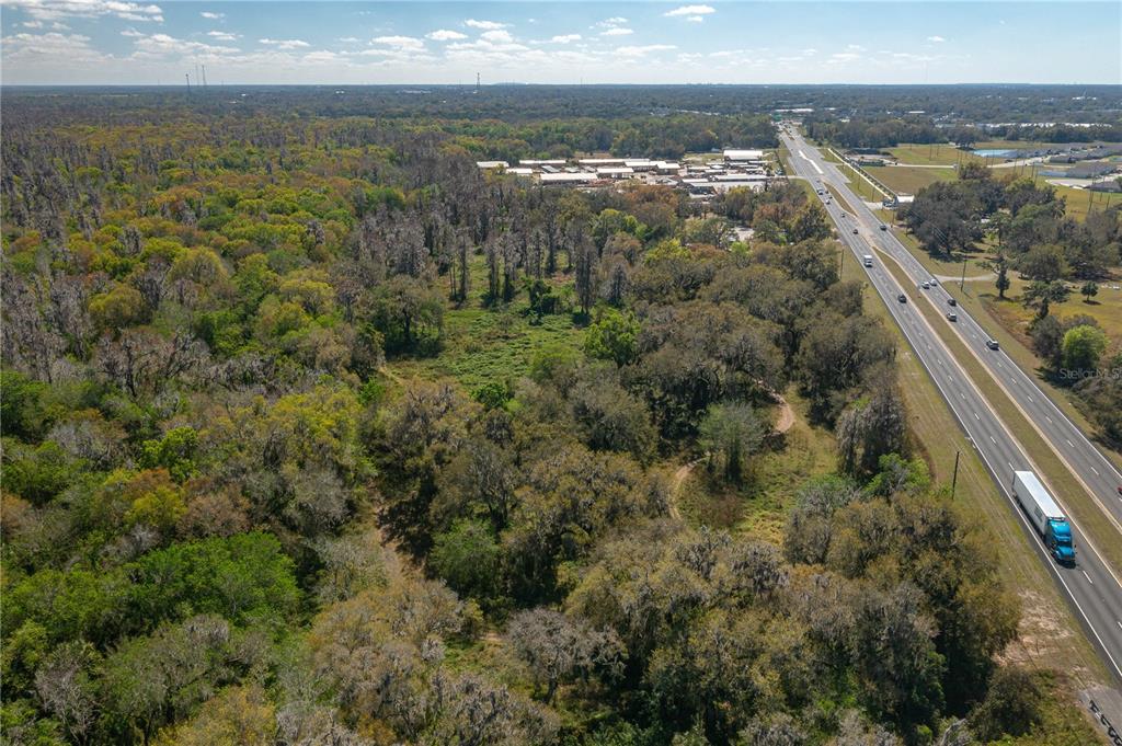 An aerial view of a wooded lot adjacent to a multi-lane highway and industrial buildings — 1800 US HIGHWAY 17 N, BARTOW, FL