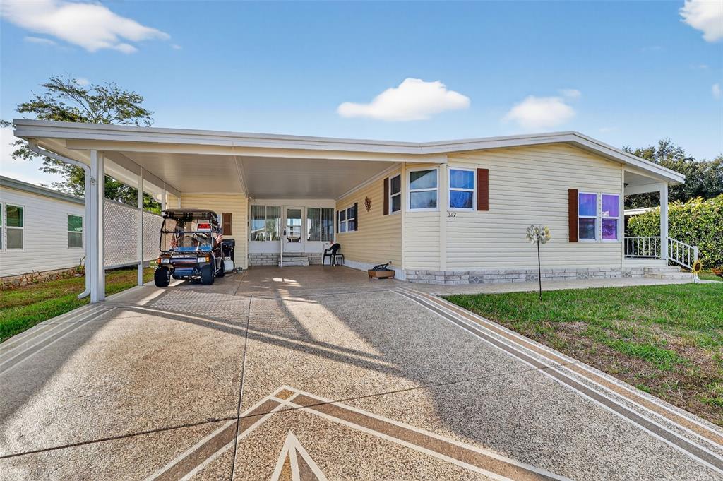A single-story house with light yellow siding, a large carport, and a concrete driveway — 3117 MANATEE ROAD, TAVARES, FL