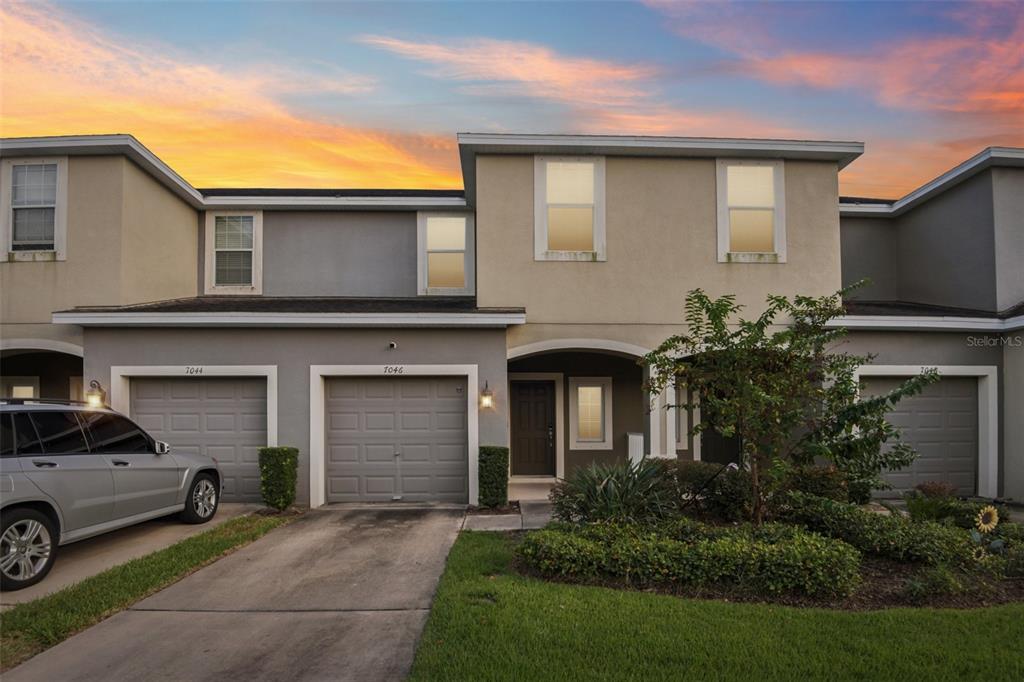 A two-story townhouse exterior features a concrete driveway, two garage doors, and a front entrance — 7046 TOWNE LAKE ROAD, RIVERVIEW, FL