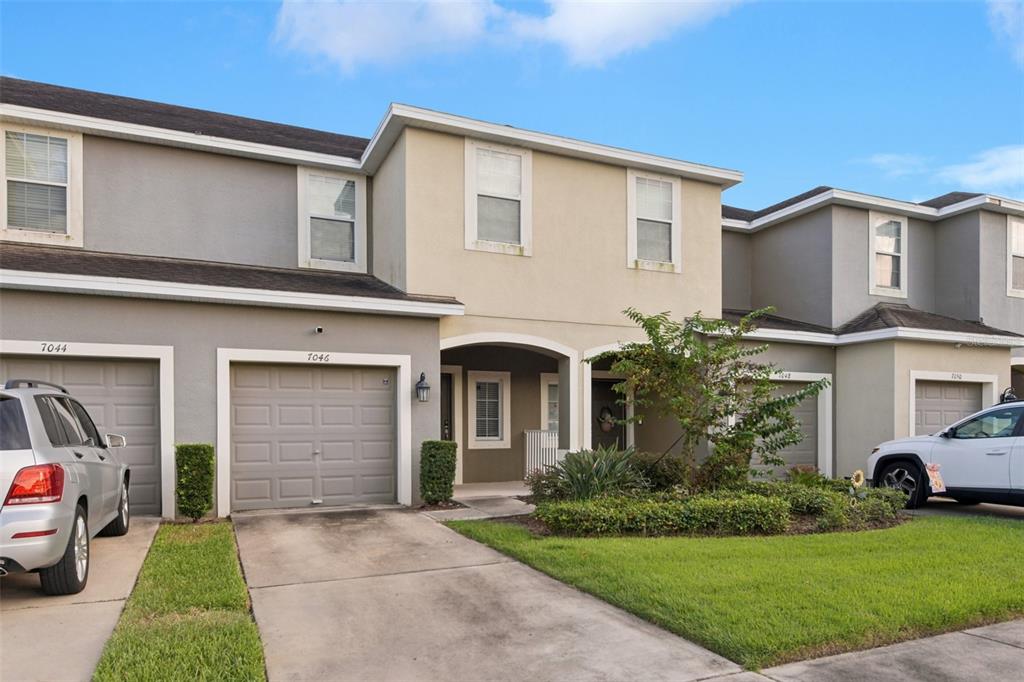 A row of multi-story townhouses features gray and tan stucco exteriors with attached garages — 7046 TOWNE LAKE ROAD, RIVERVIEW, FL