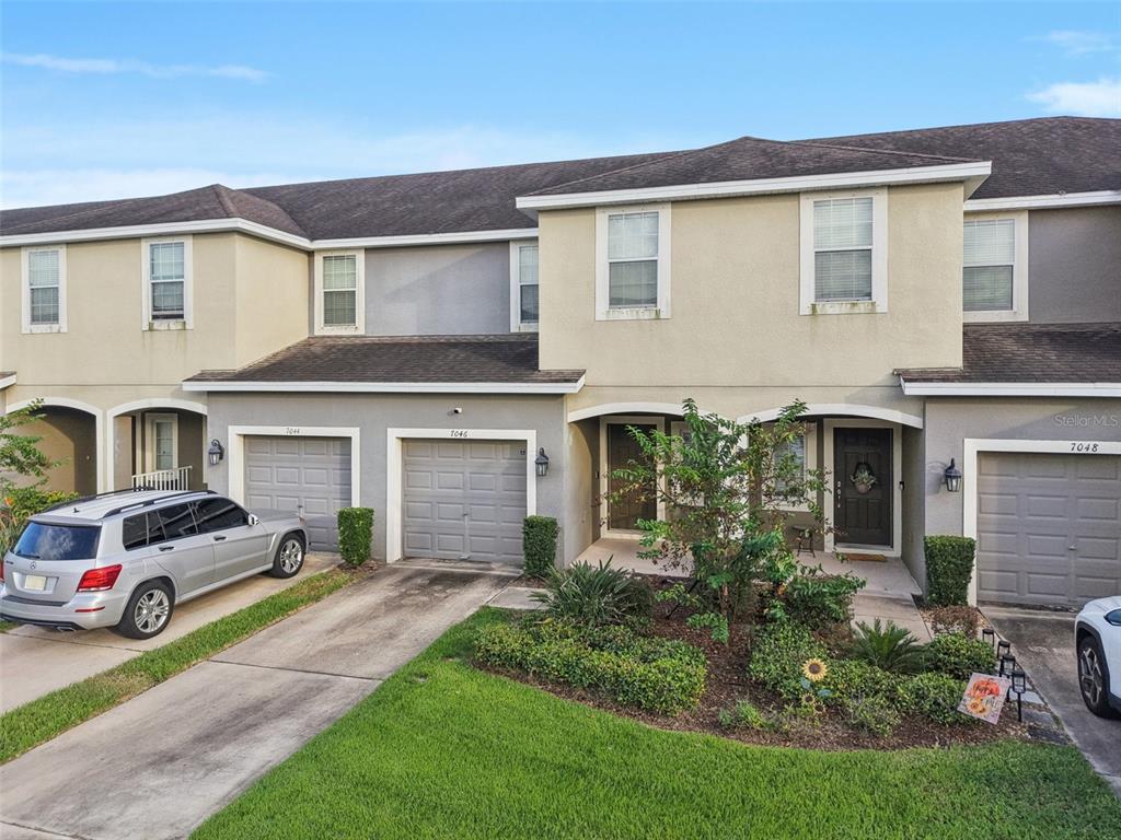 A row of multi-story townhomes with attached garages and a shared front landscaping area — 7046 TOWNE LAKE ROAD, RIVERVIEW, FL