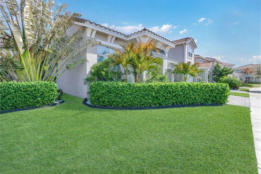 A two-story house with a manicured lawn, a large hedge, and tropical landscaping — 13321 OAKENSHAW LANE, ORLANDO, FL