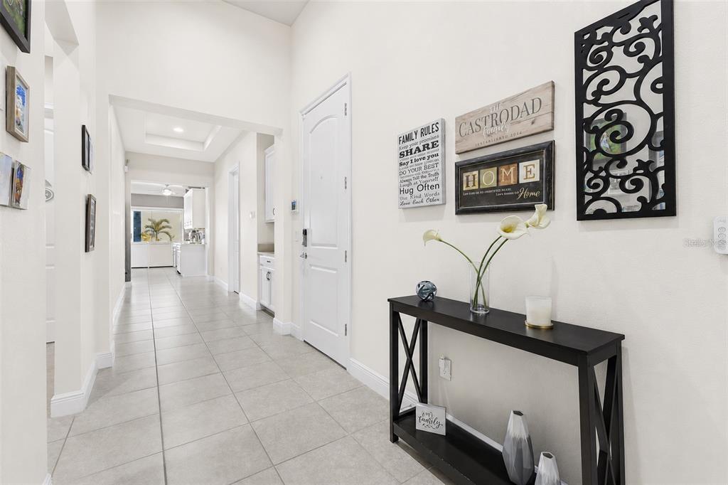 A tiled entryway features a black console table, wall decor, and a view into the kitchen — 13321 OAKENSHAW LANE, ORLANDO, FL