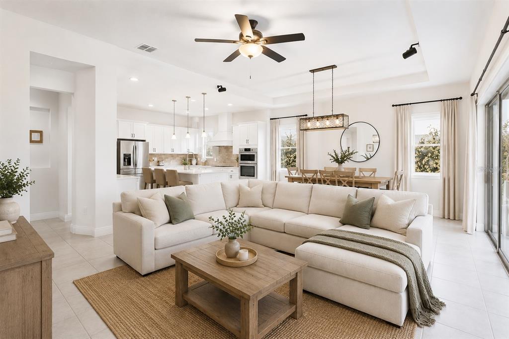 An open-concept living and dining area features a large sectional sofa and neutral decor — 13321 OAKENSHAW LANE, ORLANDO, FL