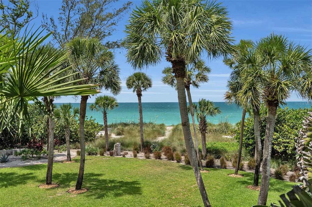 An aerial view of a large, two-story colonial-style house surrounded by palm trees at sunset — 8132 SANDERLING ROAD, SARASOTA, FL