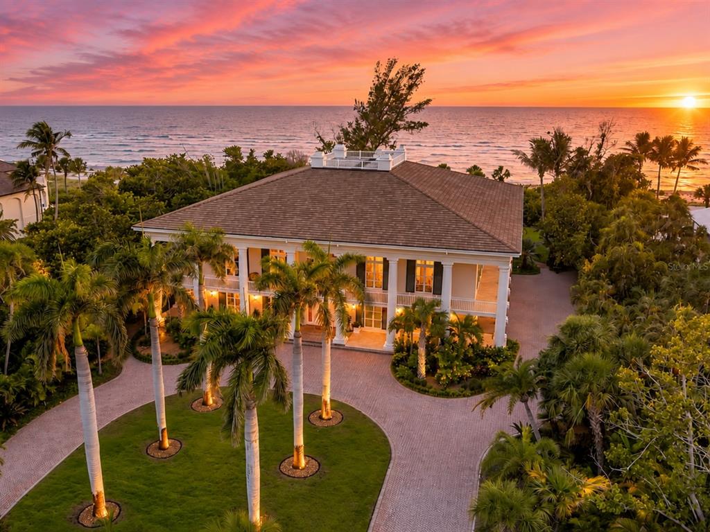 An aerial view shows a beachfront property with a large house and a vacant lot — 8132 SANDERLING ROAD, SARASOTA, FL