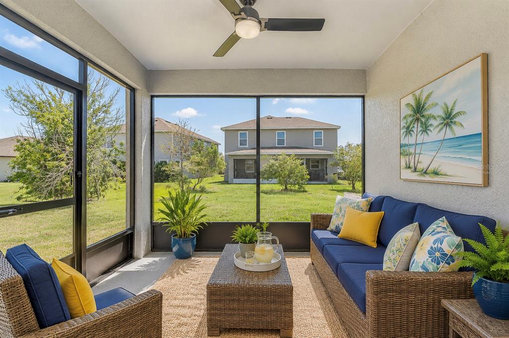 A screened-in patio features wicker furniture, a ceiling fan, and a view of a backyard — 8325 OLIVE BROOK DRIVE, WESLEY CHAPEL, FL