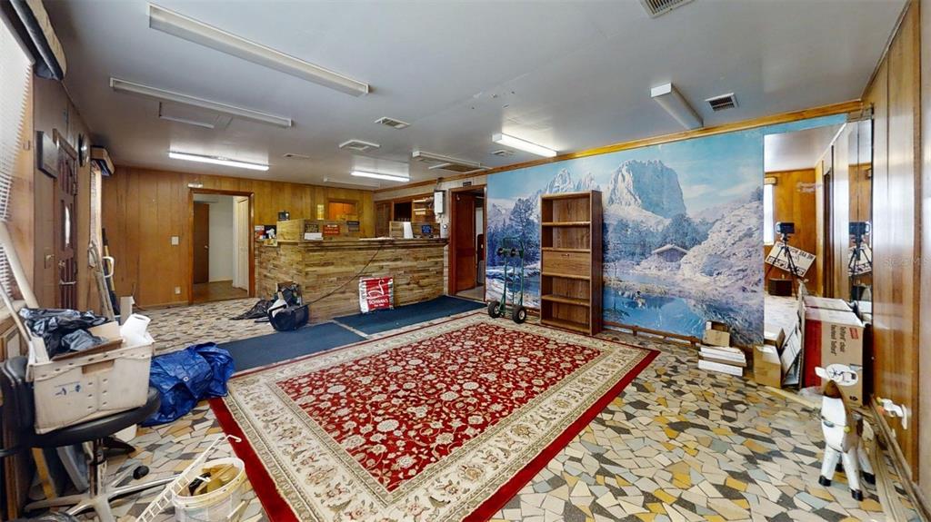 A room with wood-paneled walls, a mountain mural, a red rug, and a reception desk — 420 SE 17TH STREET, OCALA, FL