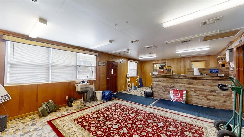 A room with wood-paneled walls, a large red patterned rug, and a service counter — 420 SE 17TH STREET, OCALA, FL