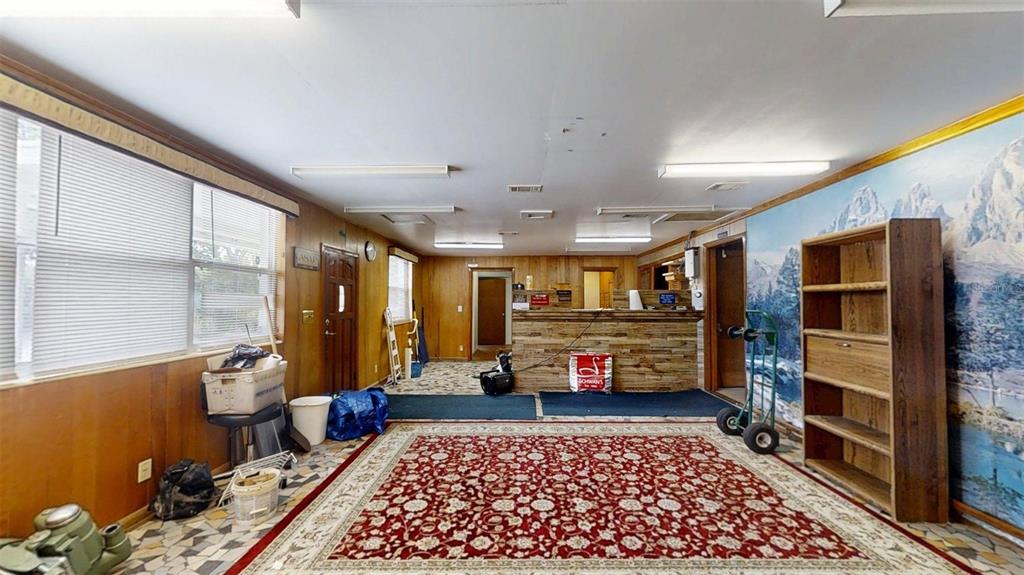 A room with wood-paneled walls, a large rug, a service counter, and a mountain mural — 420 SE 17TH STREET, OCALA, FL