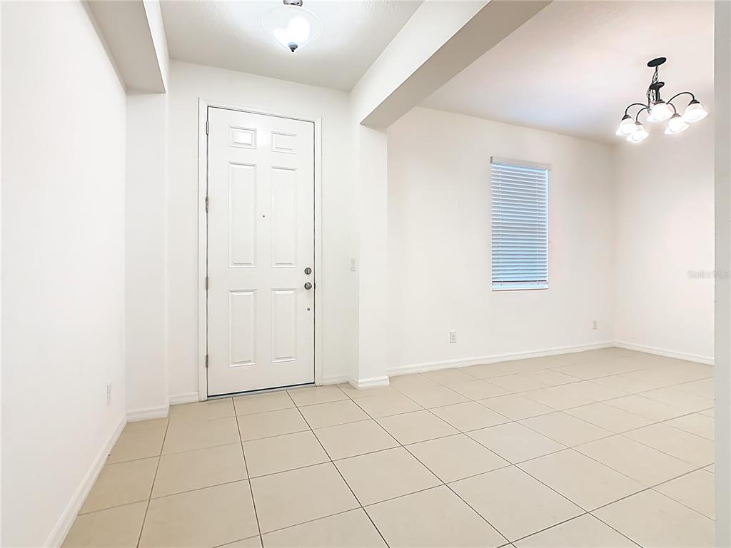 An entryway with a white door, tile flooring, and a dining area with a chandelier — 806 BENJAMIN TRAIL, DAVENPORT, FL