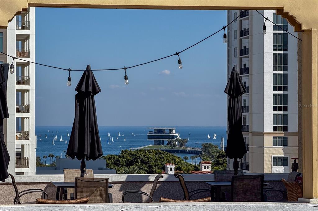 A balcony view features patio furniture, string lights, and a scenic outlook over the water — 130 4TH AVENUE N UNIT 107, ST PETERSBURG, FL