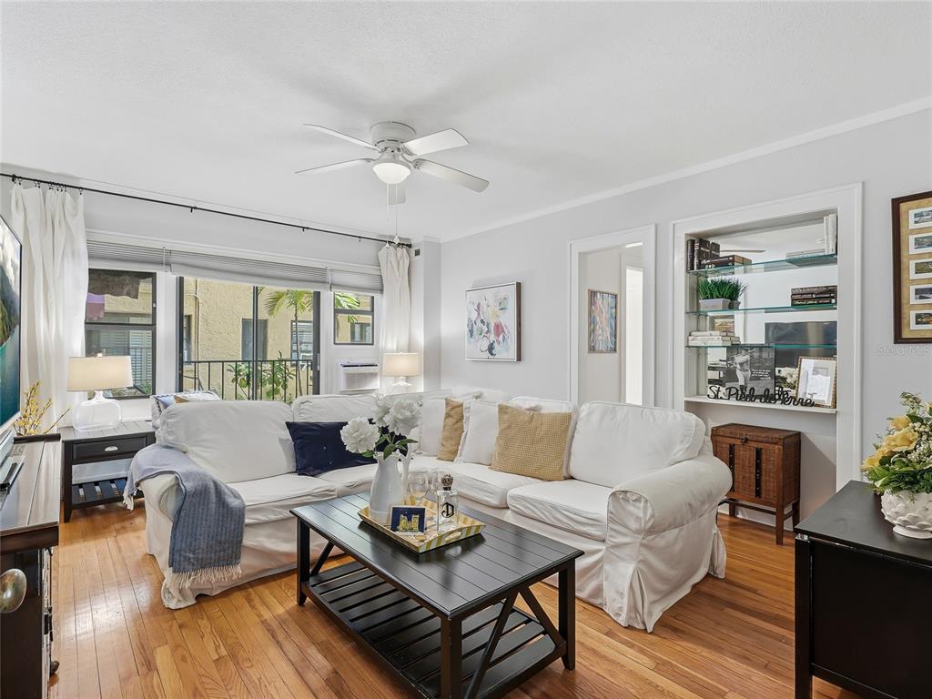 A living room features a white sectional sofa, a black coffee table, and built-in shelving — 130 4TH AVENUE N UNIT 107, ST PETERSBURG, FL