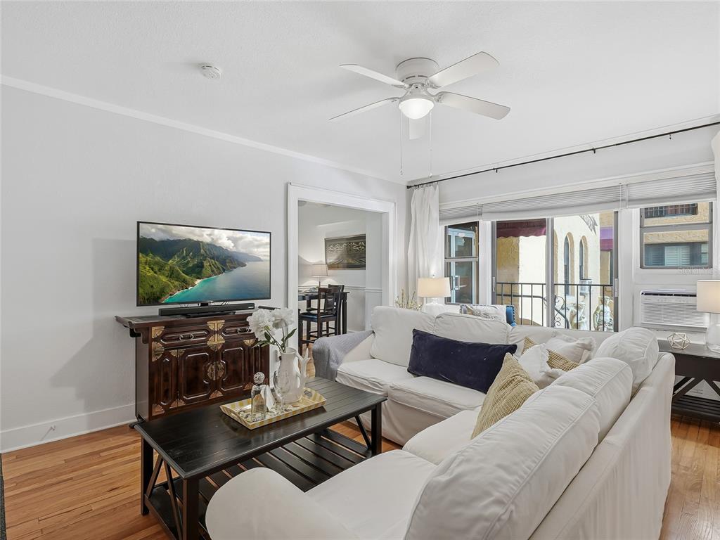A living room features a white sectional sofa, a dark wood media console, and hardwood floors — 130 4TH AVENUE N UNIT 107, ST PETERSBURG, FL