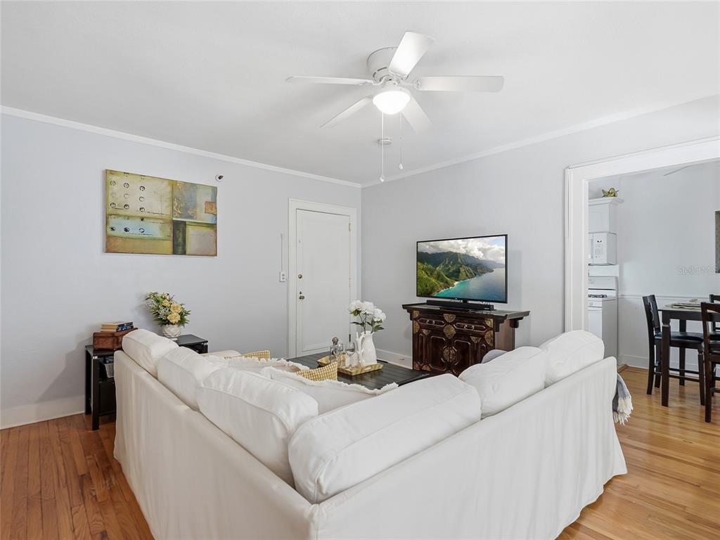 A living room features a white sectional sofa, hardwood floors, and a ceiling fan — 130 4TH AVENUE N UNIT 107, ST PETERSBURG, FL