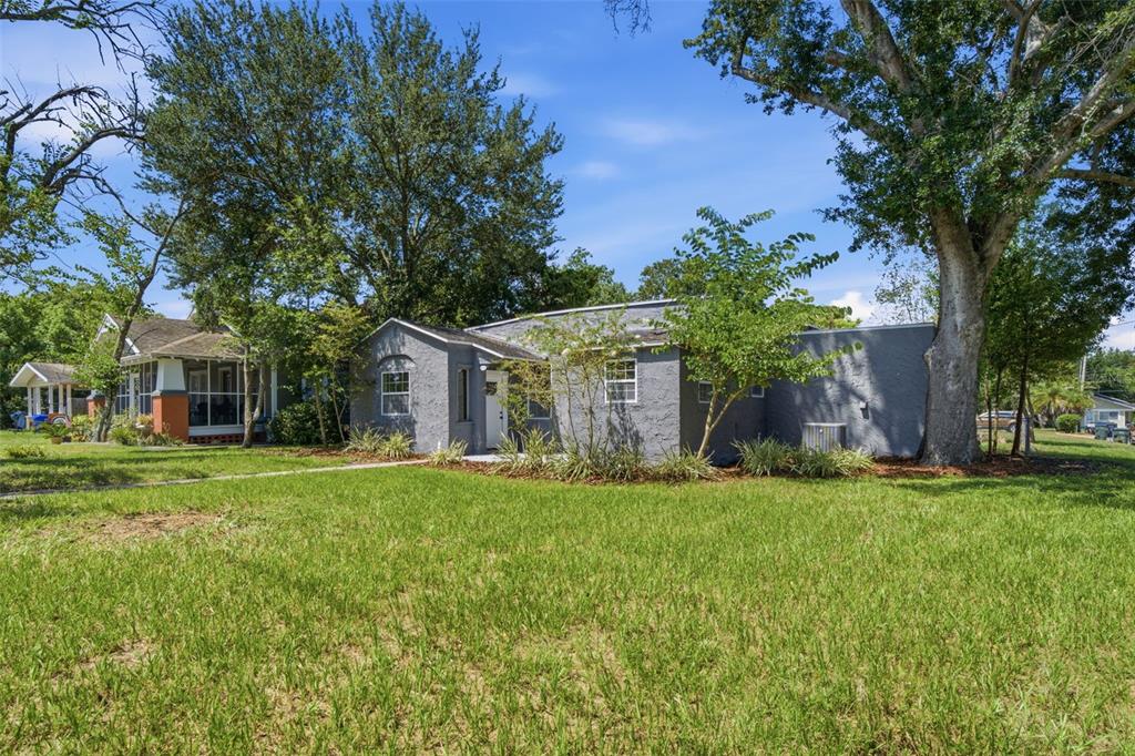 A gray stucco house with a flat roof sits on a grassy lot with trees — 1201 S LINCOLN AVENUE, LAKELAND, FL