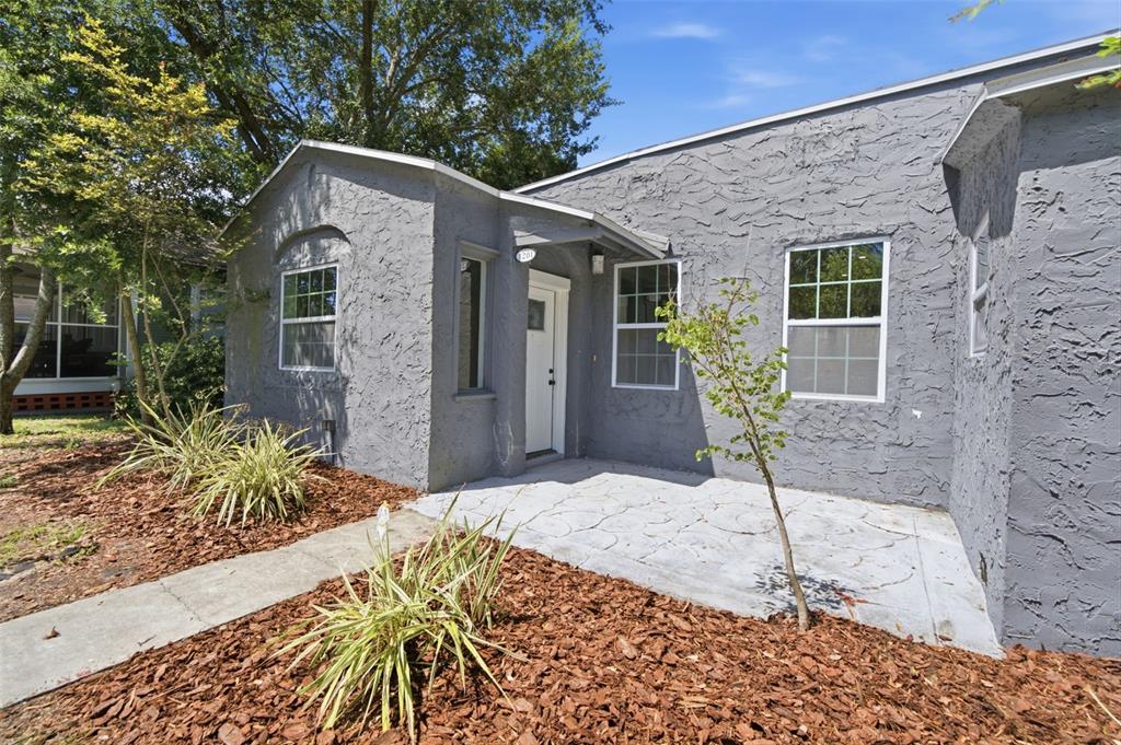 The exterior of a gray stucco house features a small front porch and walkway — 1201 S LINCOLN AVENUE, LAKELAND, FL