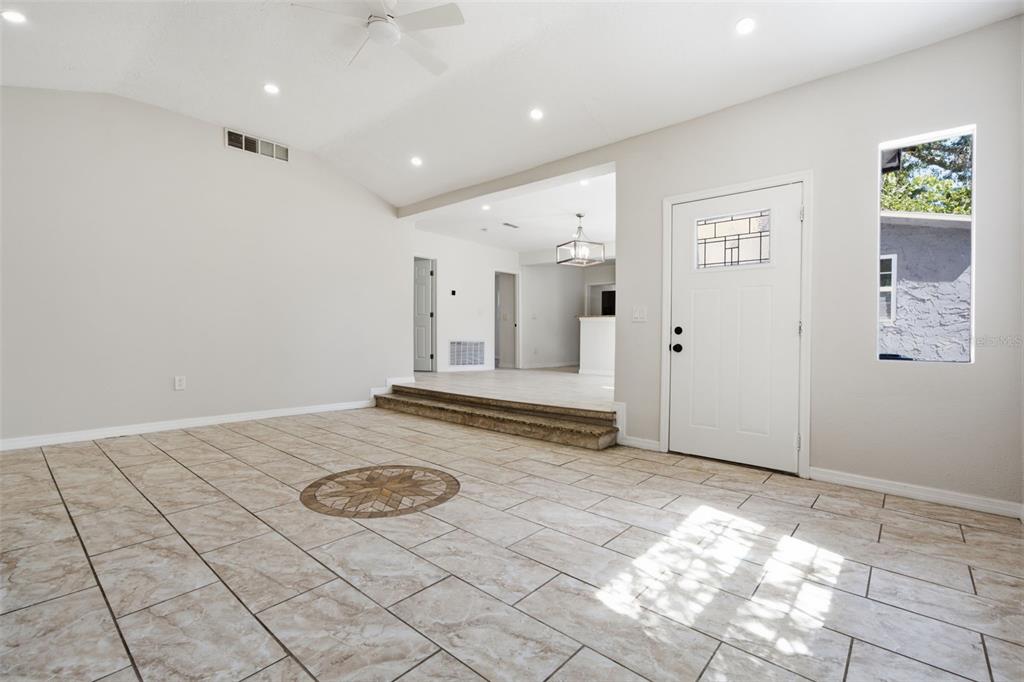 A living room with light-colored tile flooring, a decorative medallion, and a step up — 1201 S LINCOLN AVENUE, LAKELAND, FL