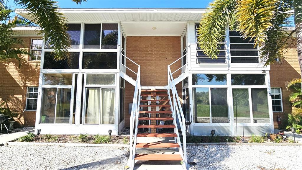A two-story brick apartment building features screened-in porches and a central outdoor staircase — 3586 CAPEHAZE DRIVE UNIT B4, ROTONDA WEST, FL