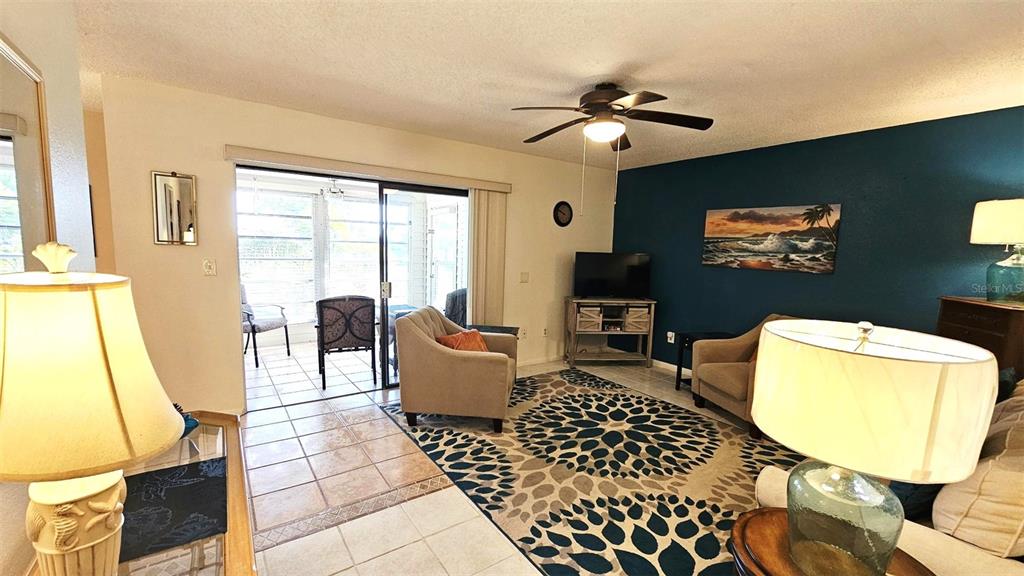 A living room features a blue accent wall, a patterned area rug, and sliding glass doors — 3586 CAPEHAZE DRIVE UNIT B4, ROTONDA WEST, FL