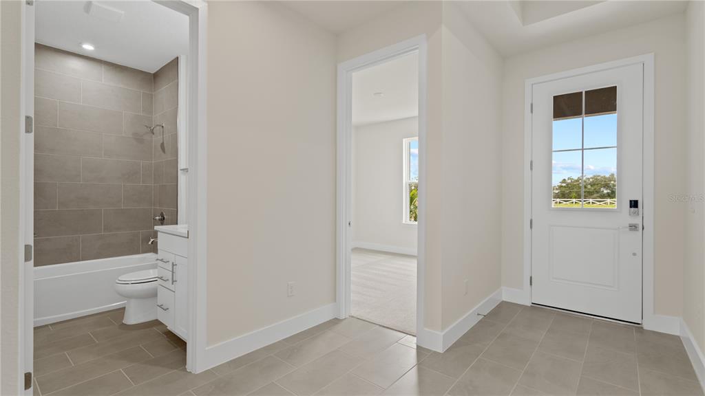 A tiled entryway leads to a bathroom with a tub-shower combo and a carpeted bedroom — 30273 RUSTIC MILL STREET, MOUNT DORA, FL