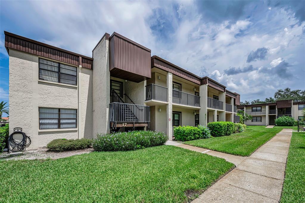 A two-story apartment building with stucco walls, brown trim, and an exterior staircase — 2400 WINDING CREEK BOULEVARD UNIT 17-103, CLEARWATER, FL