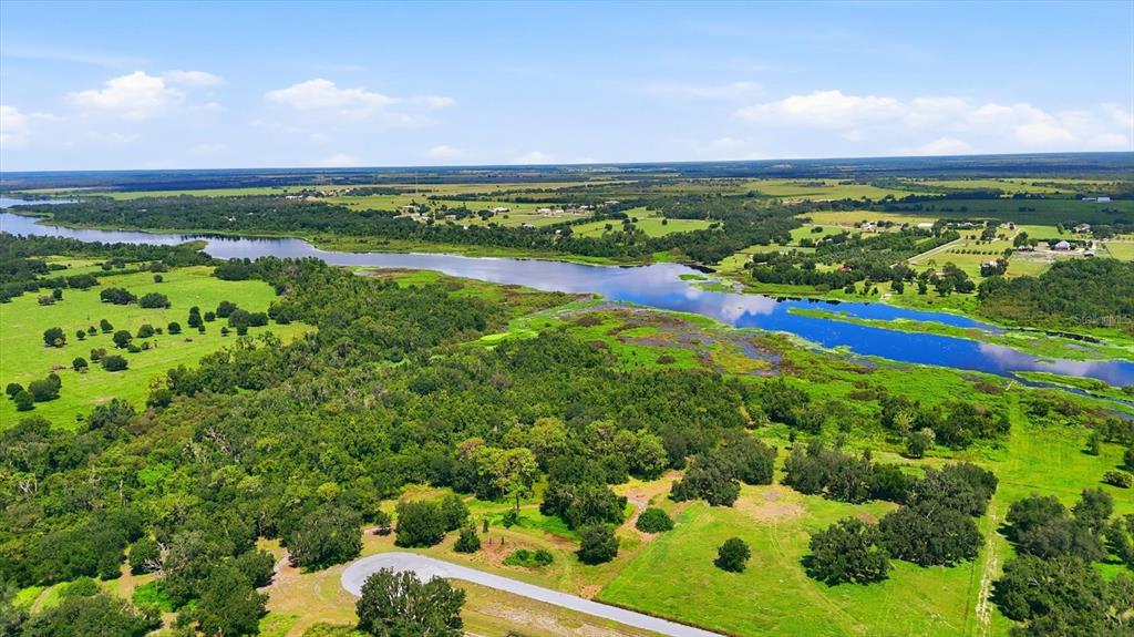 An aerial view shows a winding river flowing through a landscape of green fields and trees — 26125 39TH PL E BOULEVARD, MYAKKA CITY, FL
