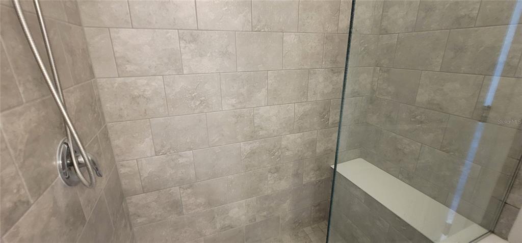 A walk-in shower with gray subway tiles, a glass door, and a built-in bench — 1908 FLORA PASS PLACE, KISSIMMEE, FL