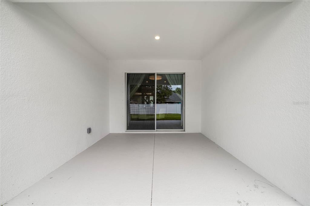 A covered patio features white walls, a gray concrete floor, and a sliding glass door — 3181 LA FRANCE AVENUE SW, PALM BAY, FL