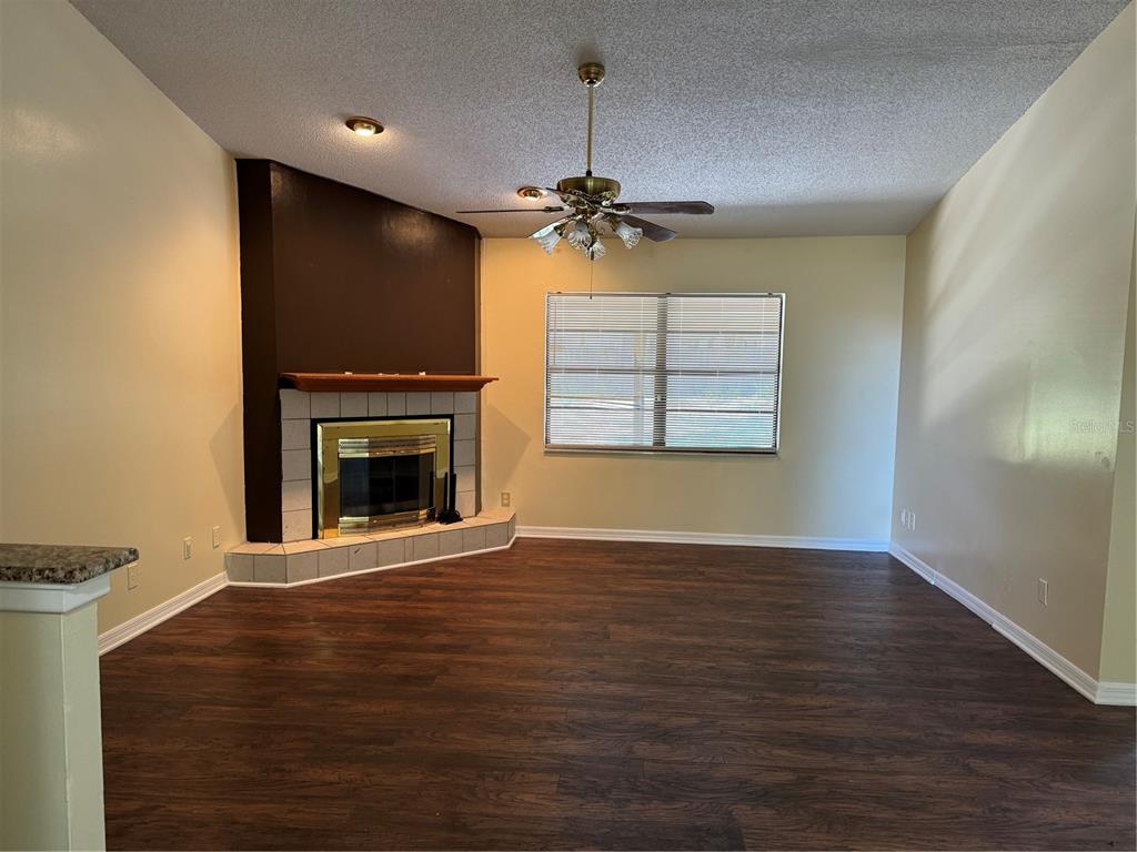 A living room features dark wood-look flooring, a corner fireplace with tile, and a ceiling fan — 5581 AEOLUS WAY, ORLANDO, FL