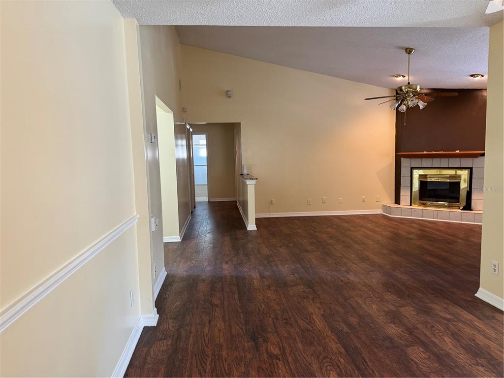 A living room with wood-look flooring, a vaulted ceiling, and a fireplace with a mantel — 5581 AEOLUS WAY, ORLANDO, FL