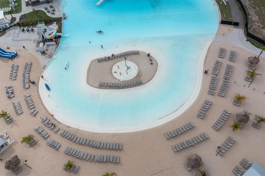 An aerial view shows a large turquoise swimming lagoon with a central sandy island — 17070 OVAL RUM DRIVE, WIMAUMA, FL