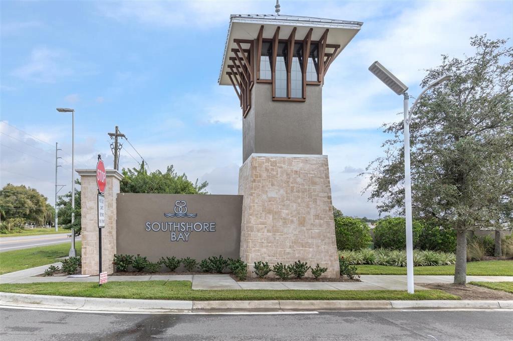 A stone monument sign for Southshore Bay stands near a road under a cloudy sky — 17070 OVAL RUM DRIVE, WIMAUMA, FL