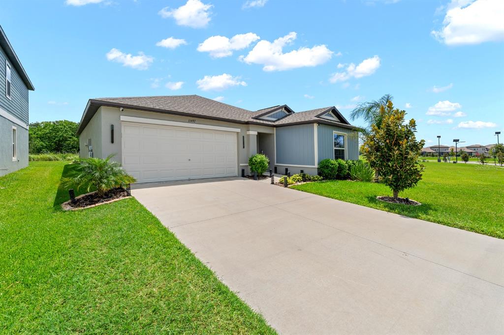 A single-story house with a two-car garage, light gray siding, and a concrete driveway — 11497 LINDEN DEPOT ROAD, SAN ANTONIO, FL