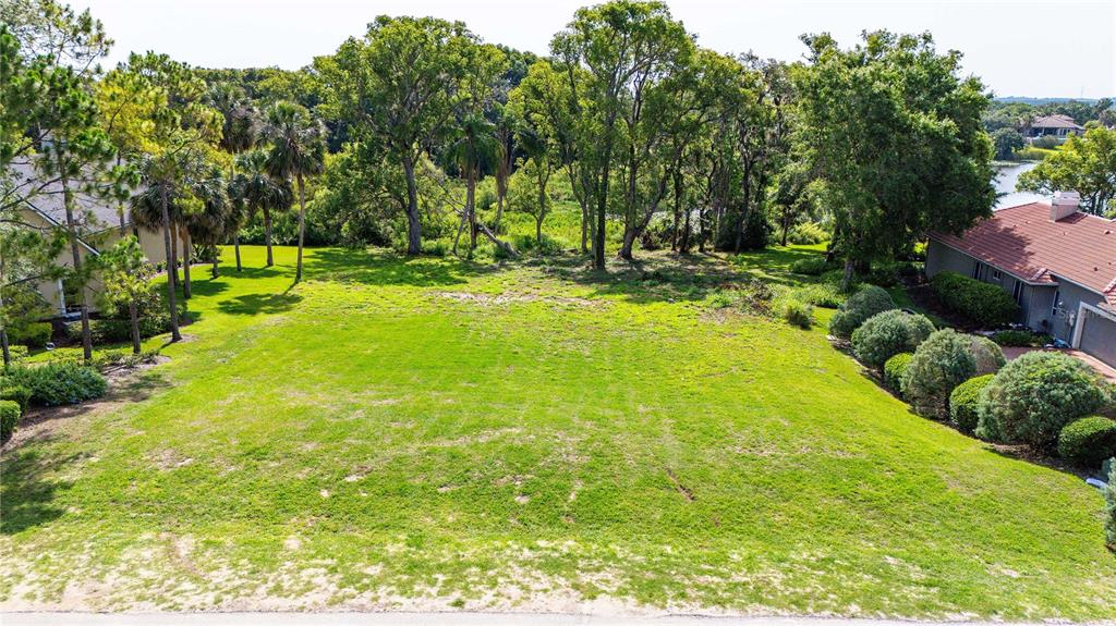 An elevated view of a vacant, grassy residential lot situated between two existing houses — 12920 VENTANA CT, DADE CITY, FL