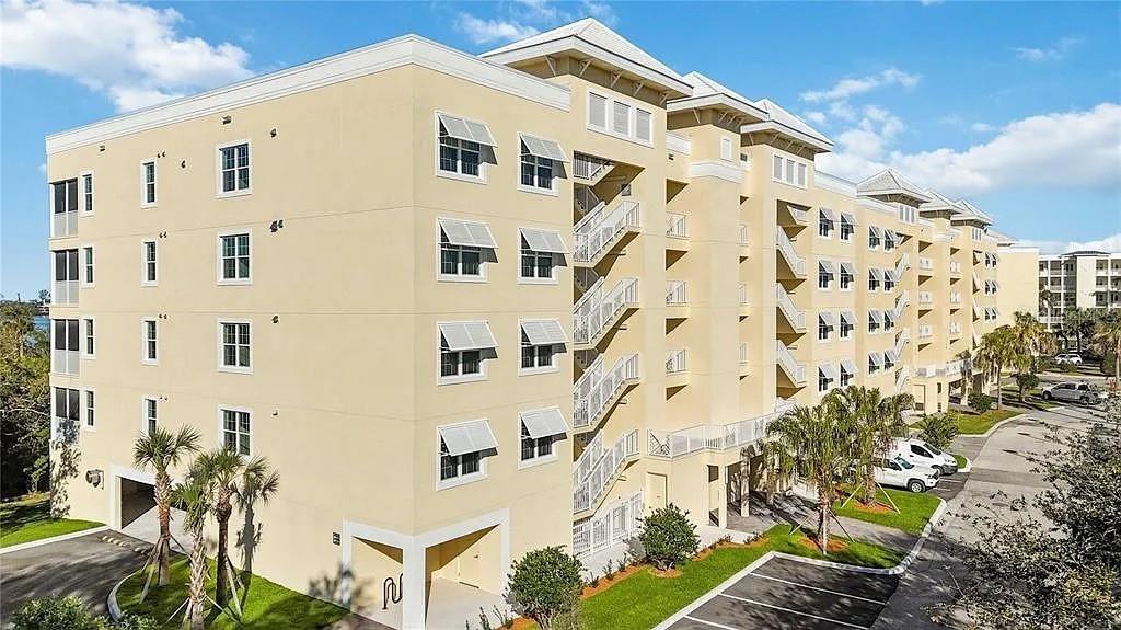 A multi-story, light yellow apartment building features external staircases and a parking area — 280 HIDDEN BAY DRIVE UNIT 302, OSPREY, FL