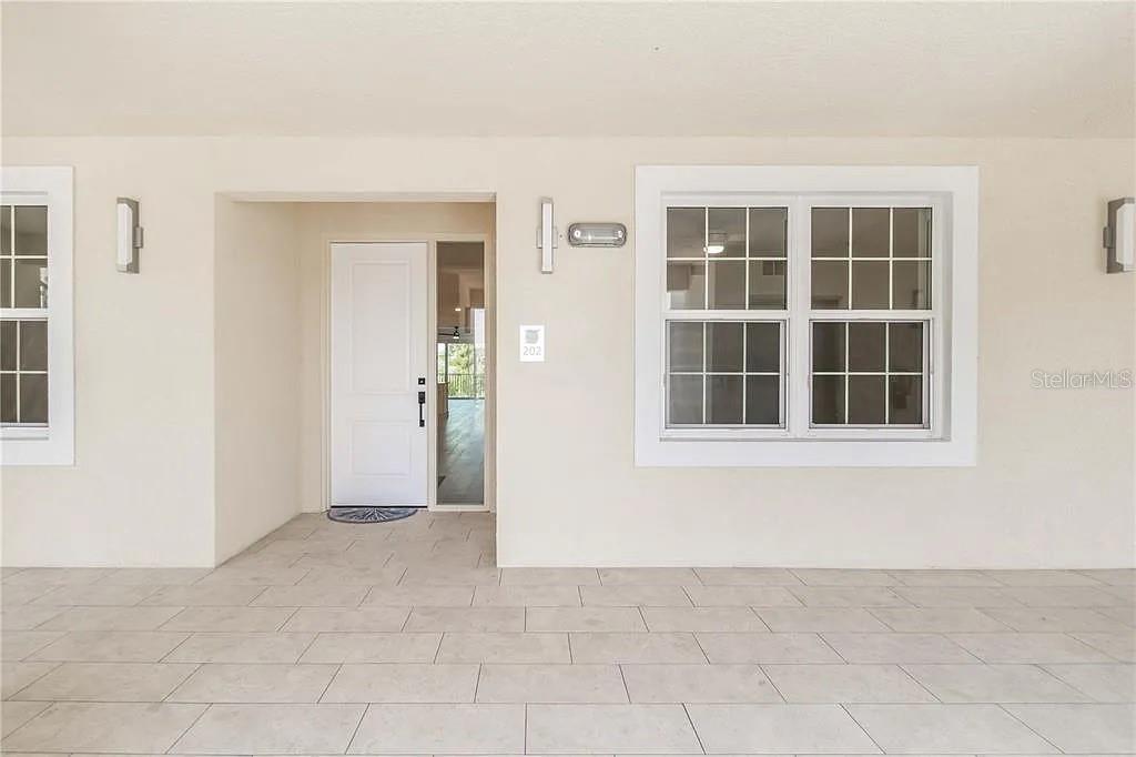 The exterior entryway features a white door, a large window, and light-colored tiled flooring — 280 HIDDEN BAY DRIVE UNIT 302, OSPREY, FL