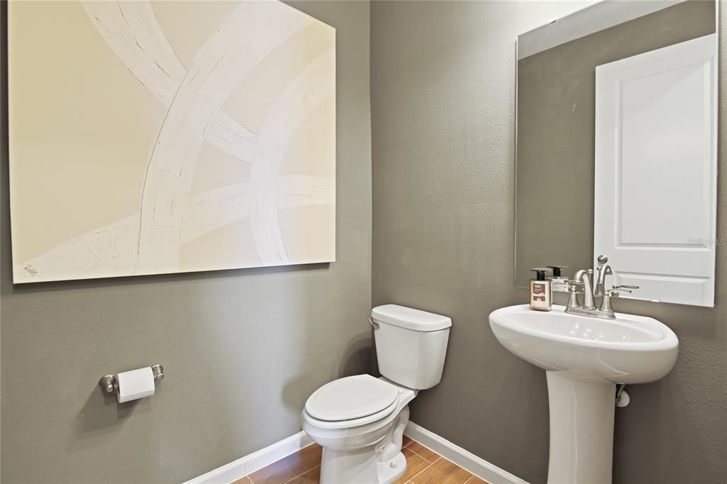 A powder room features a pedestal sink, a white toilet, and abstract wall art — 5314 SPRING MAIDEN CIRCLE, APOLLO BEACH, FL