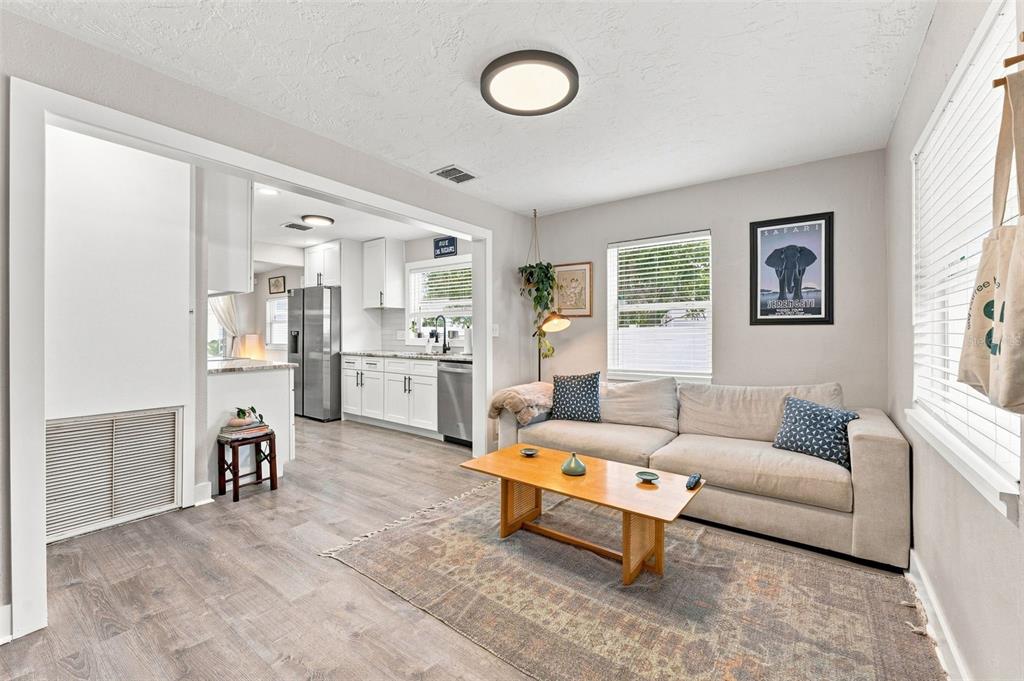 A living room with a beige sofa, wooden coffee table, and an open kitchen beyond — 4819 20TH STREET N, ST PETERSBURG, FL