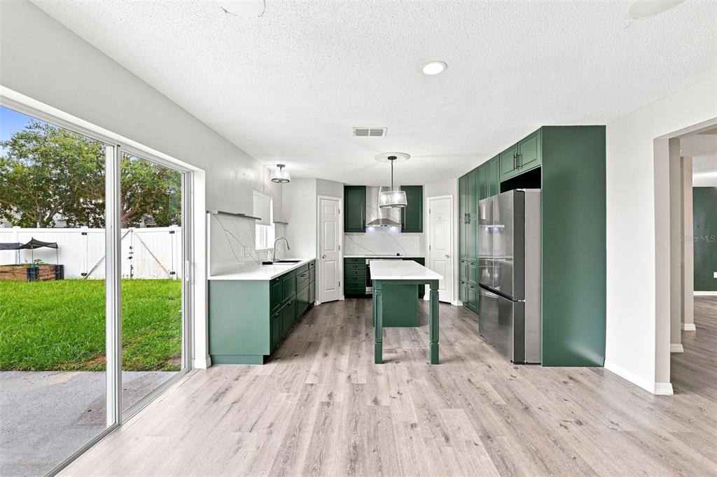 A kitchen with green cabinets, a central island, and a sliding door to the backyard — 10464 FLY FISHING STREET, RIVERVIEW, FL