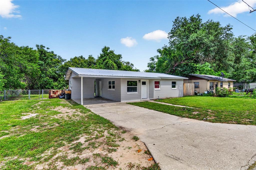 A single-story gray house with a metal roof and an attached carport — 14002 MORGAN ST, DADE CITY, FL