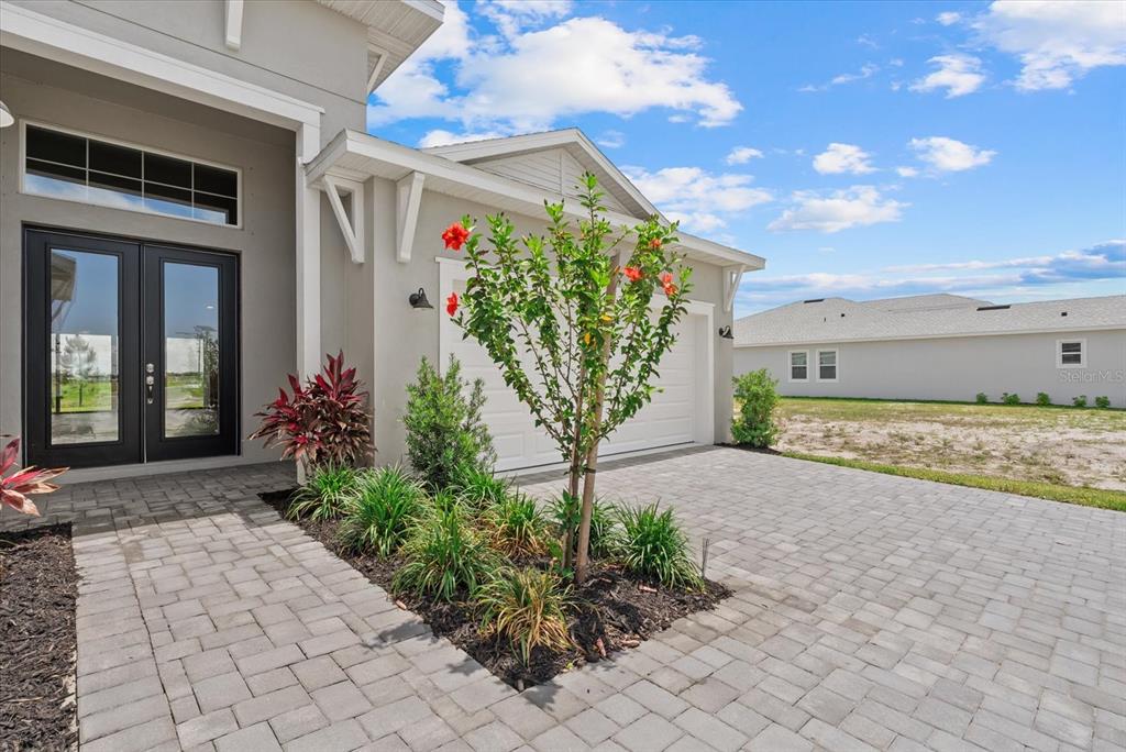 A paved driveway leads to the front entrance and garage of a modern suburban home — 8668 SALMAR LOOP, PARRISH, FL