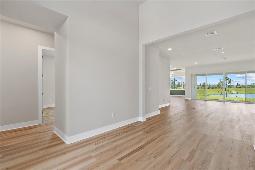 An interior view shows a bright living area with light wood flooring and sliding glass doors — 8668 SALMAR LOOP, PARRISH, FL