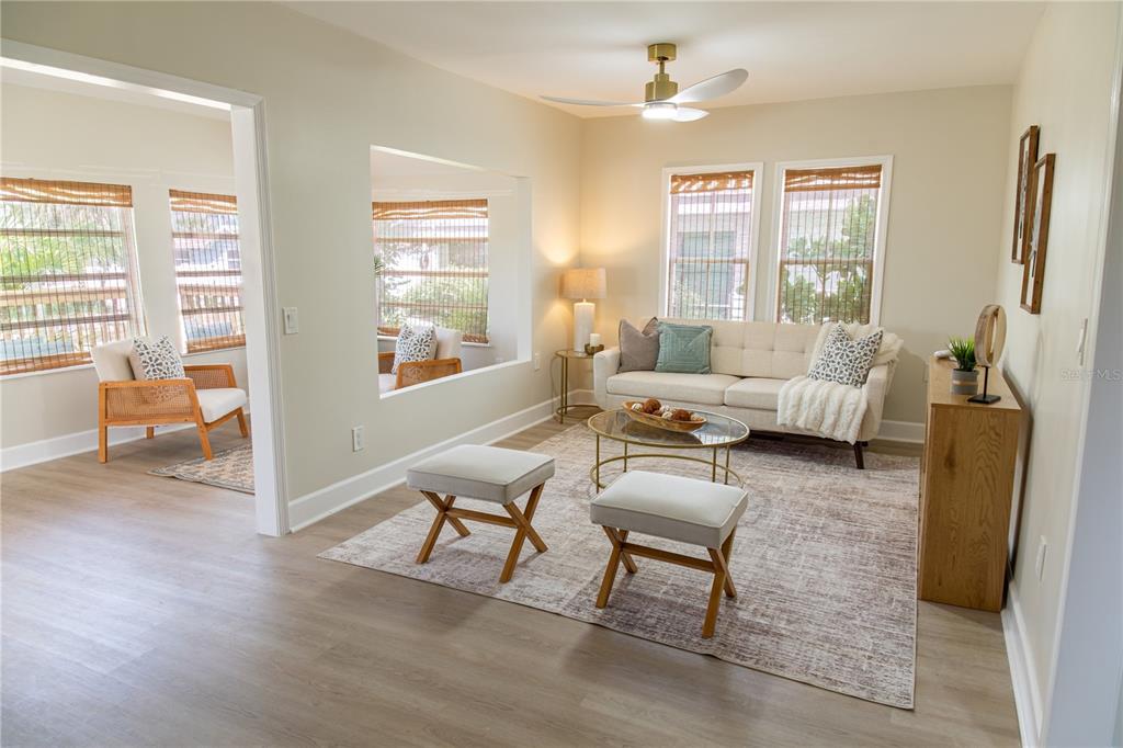 A living room features a beige sofa, two ottomans, a coffee table, and light flooring — 13148 3RD STREET E, MADEIRA BEACH, FL