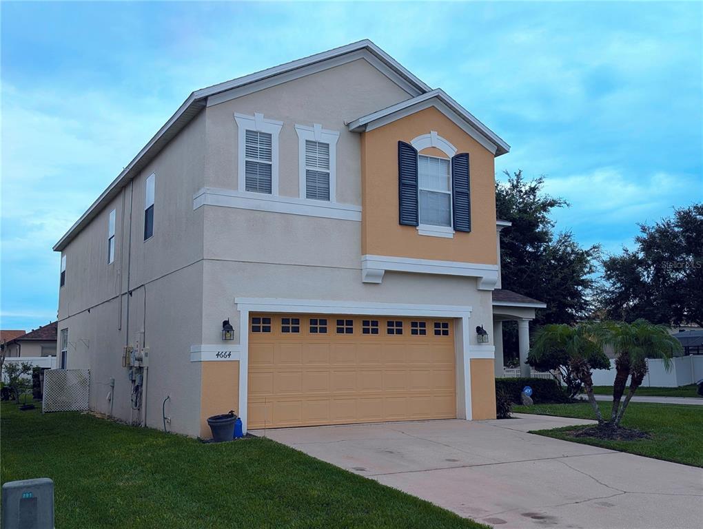 A two-story suburban house with a tan stucco exterior and a two-car garage — 4664 CAVERNS DRIVE, KISSIMMEE, FL