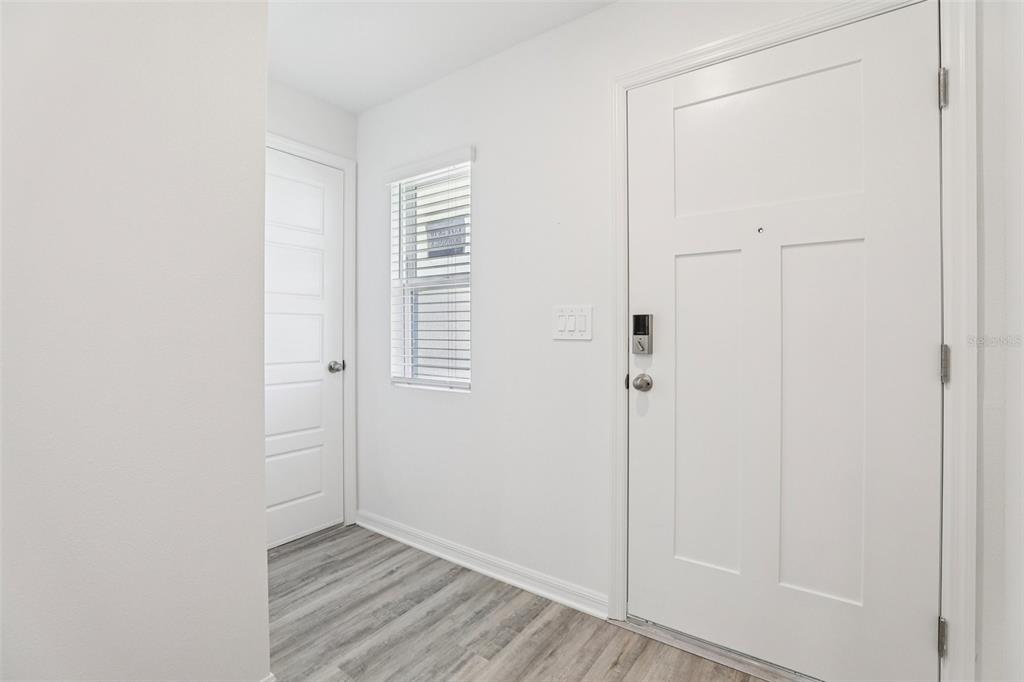 An entryway with white walls, light wood-look flooring, a window, and two white doors — 3328 WHITE INDIGO ROAD, WINTER HAVEN, FL