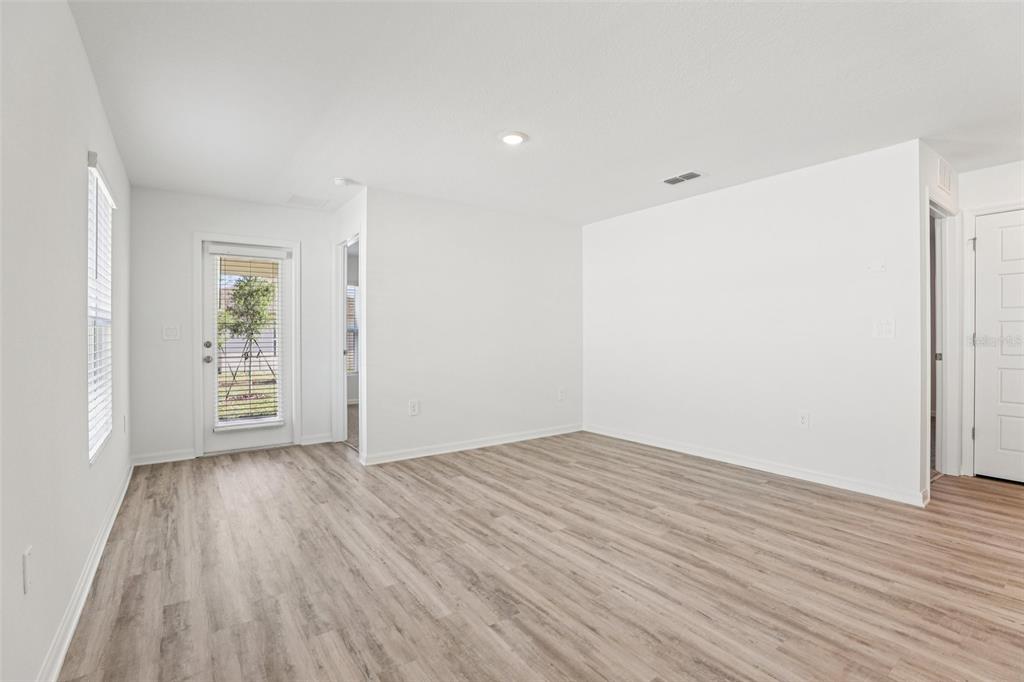 An empty room with light wood-look flooring, white walls, a glass door, and recessed lighting — 3328 WHITE INDIGO ROAD, WINTER HAVEN, FL