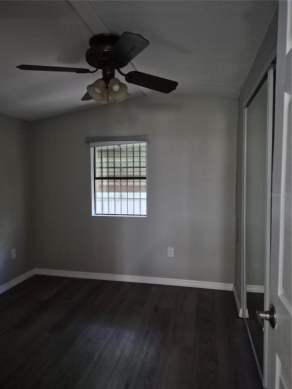 A bedroom with gray walls, dark wood-look flooring, a ceiling fan, and a mirrored closet — 3000 CLARCONA ROAD UNIT 532, APOPKA, FL