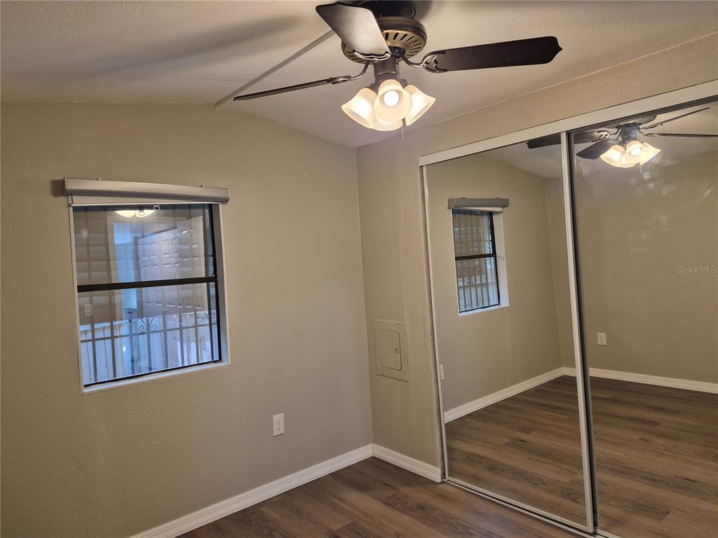 A bedroom with light-colored walls, wood-look flooring, a ceiling fan, and mirrored closet doors — 3000 CLARCONA ROAD UNIT 532, APOPKA, FL