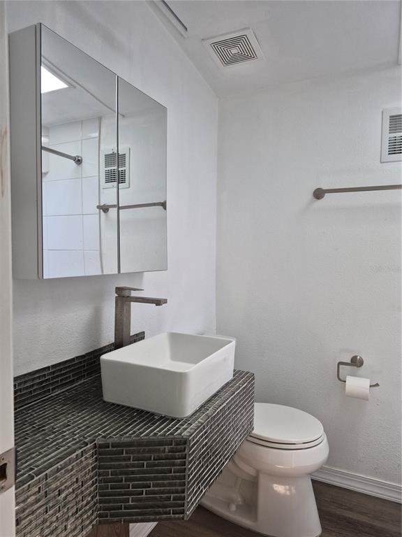 A bathroom features a vessel sink on a tiled vanity, a mirror cabinet, and toilet — 3000 CLARCONA ROAD UNIT 532, APOPKA, FL